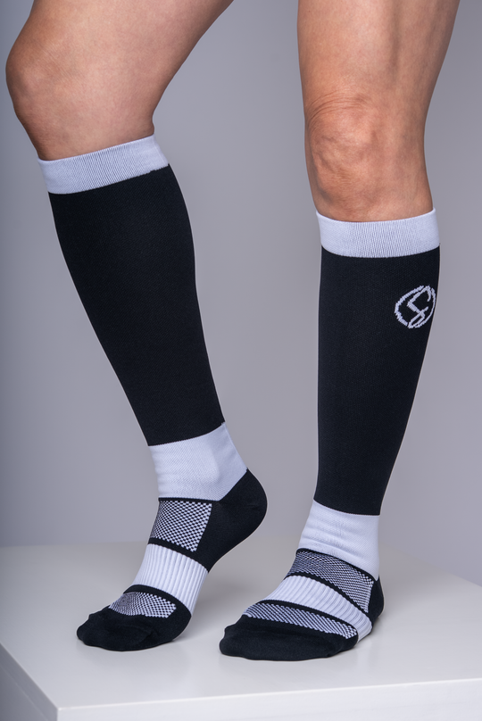Black and white knee-high socks with a logo on a gray background