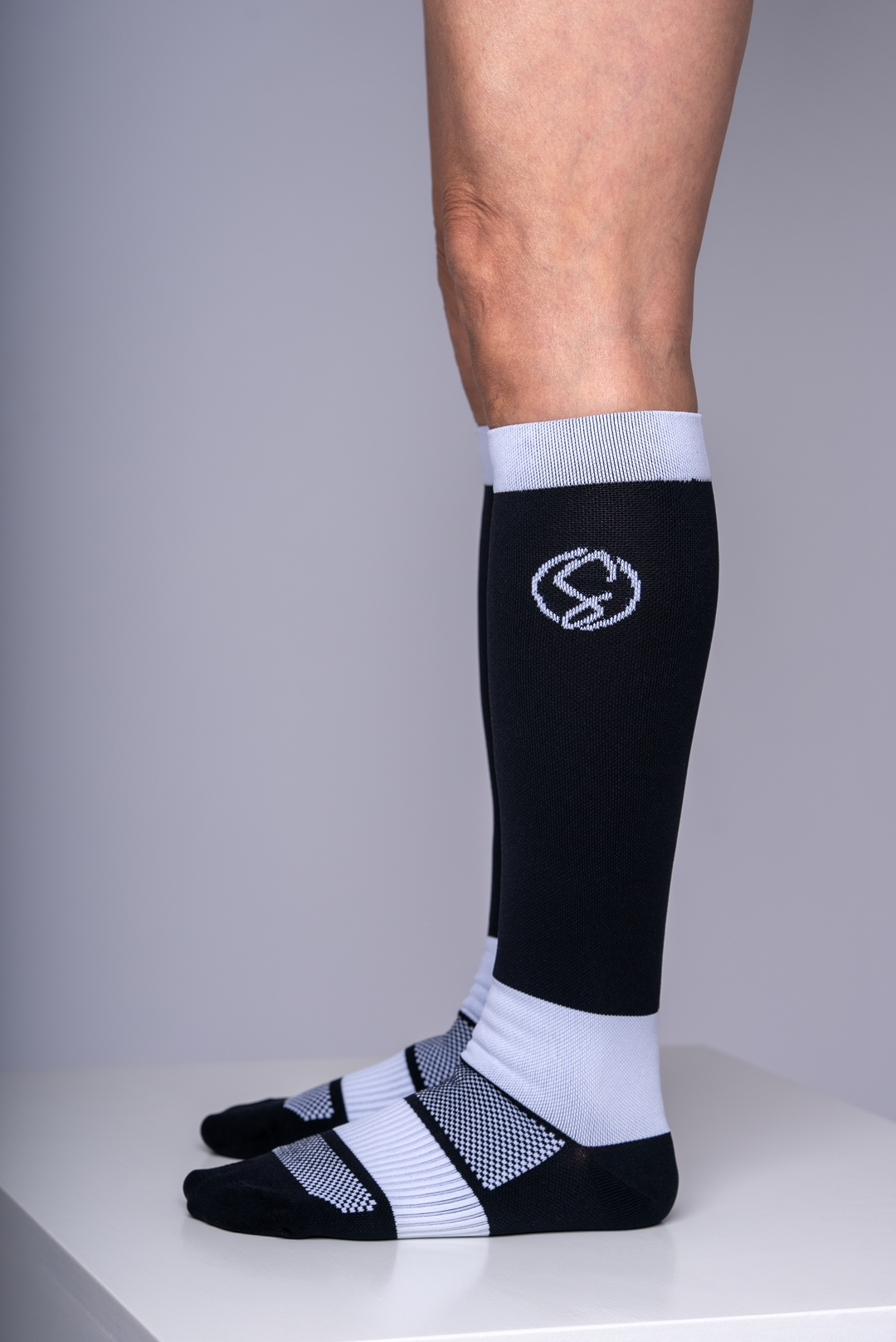 Black compression socks with a logo on a gray background