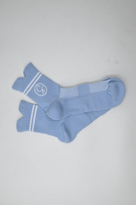 Pair of light blue socks with white stripes on a gray background