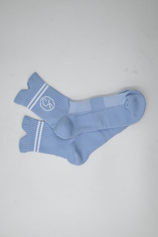 Pair of light blue socks with white stripes on a gray background